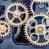 Close-up view of several interlocking brass gears inside a mechanical device, showing their teeth and intricate design.